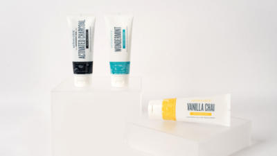 Two Schmidt's toothpastes standing vertically on clear frosted lucite platform, one toothpaste laying horizontally on a clear lucite platform, with white background